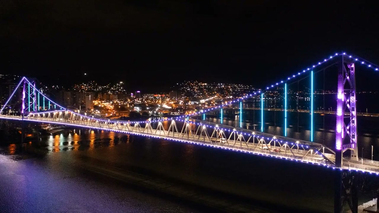 Ponte Hercílio Luz iluminada à noite, imagem de fechamento do site da Ilha Sites SC